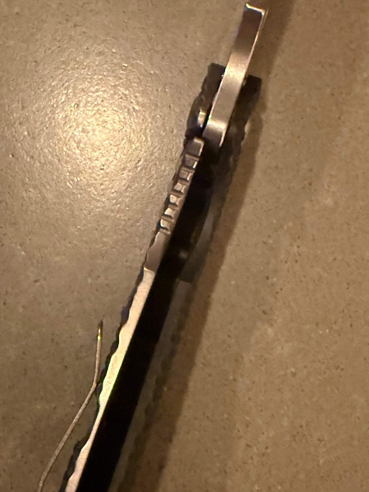 Close-up of Strider SMF DGG showing blade spine, aggressive jimping and open-back G10 and titanium construction.