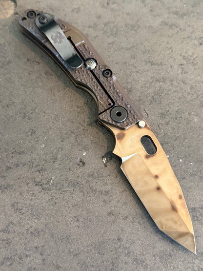 Duane Dwyer BBN-M Tanto PD1 knife showing Molten titanium frame lock, Antique Bronze finish and engraved pocket clip.