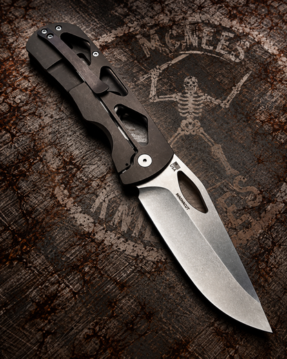 McNees Dixon 3.75 bronze skeletonized titanium frame lock knife showing satin stonewashed blade and titanium pocket clip