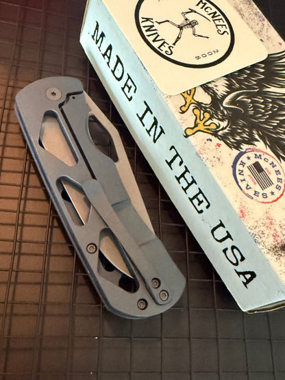 McNees Dixon 3.75 closed folding knife showing skeletonized blue titanium handle and matching pocket clip