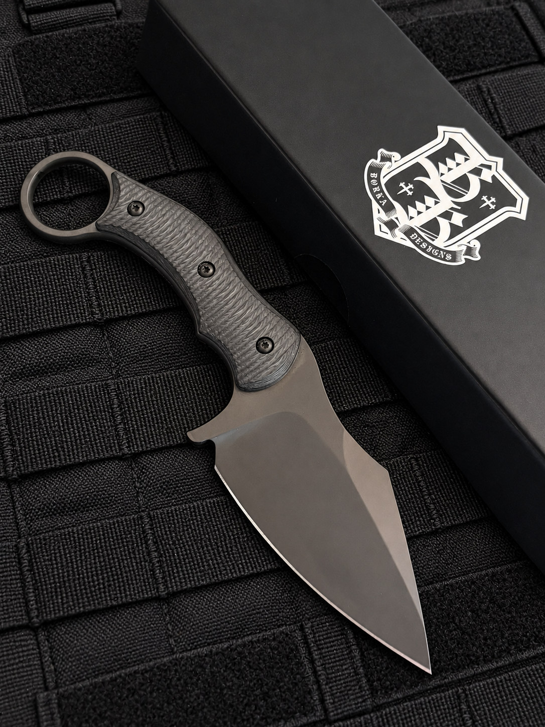 Reverse side of Borka Blades SRambit M390 fixed blade showing black PVD blade, sculpted carbon fiber handle and integrated finger ring.