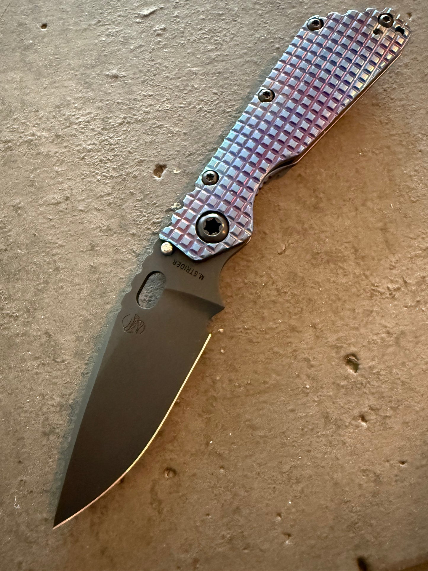 Strider SMF Monkey Edge FRAG CPM 3V spear point knife with blue and purple heat-anodized titanium presentation handle and dark blade.