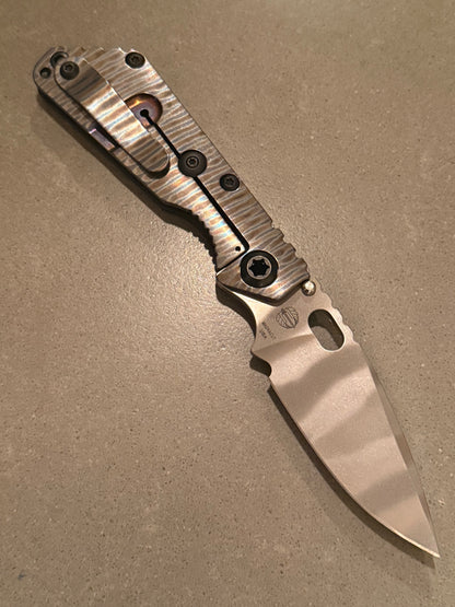Strider SnG CC CPM MagnaCut Ghost Stripe blade with polished Strider Stripe titanium frame lock, matching pocket clip, and black titanium hardware.