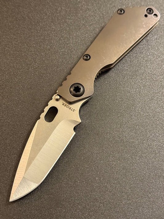 Strider SnG CC Compound Grind CPM MagnaCut folding knife with full Acid Bronze titanium handles, presentation side view.