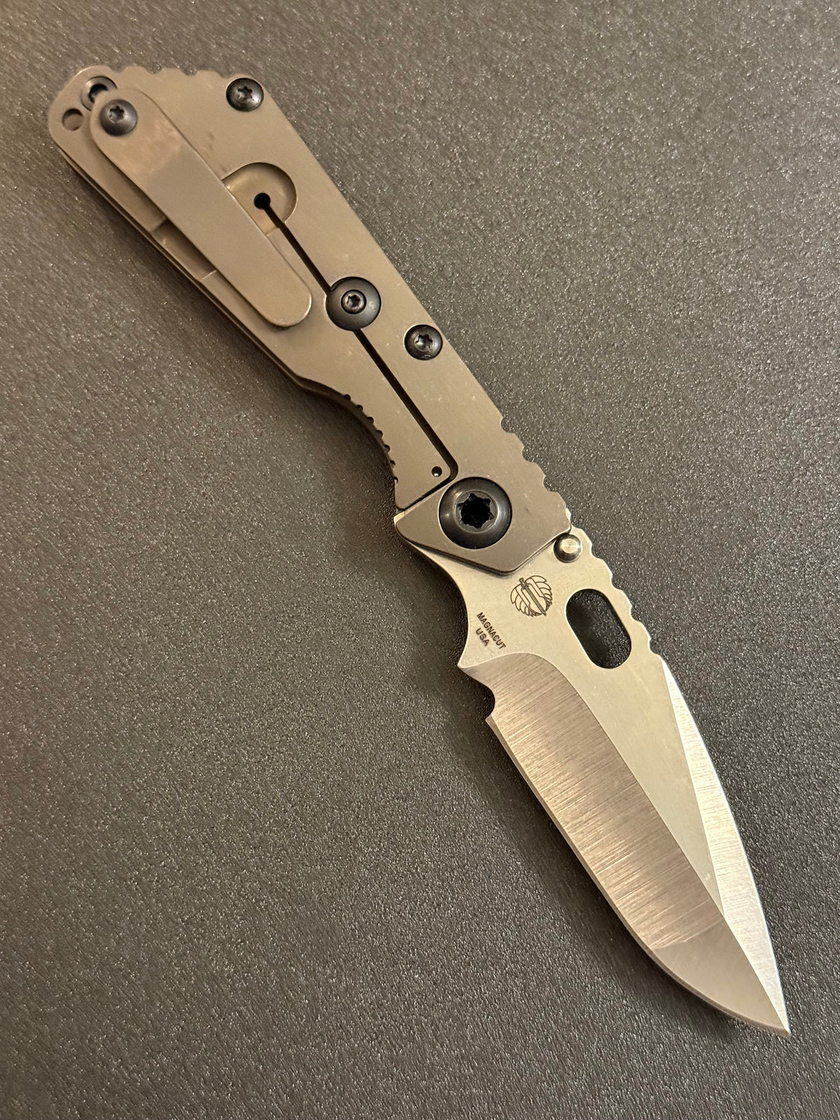 Strider SnG CC MagnaCut compound grind knife showing Acid Bronze titanium frame lock, pocket clip, and satin blade bevels.
