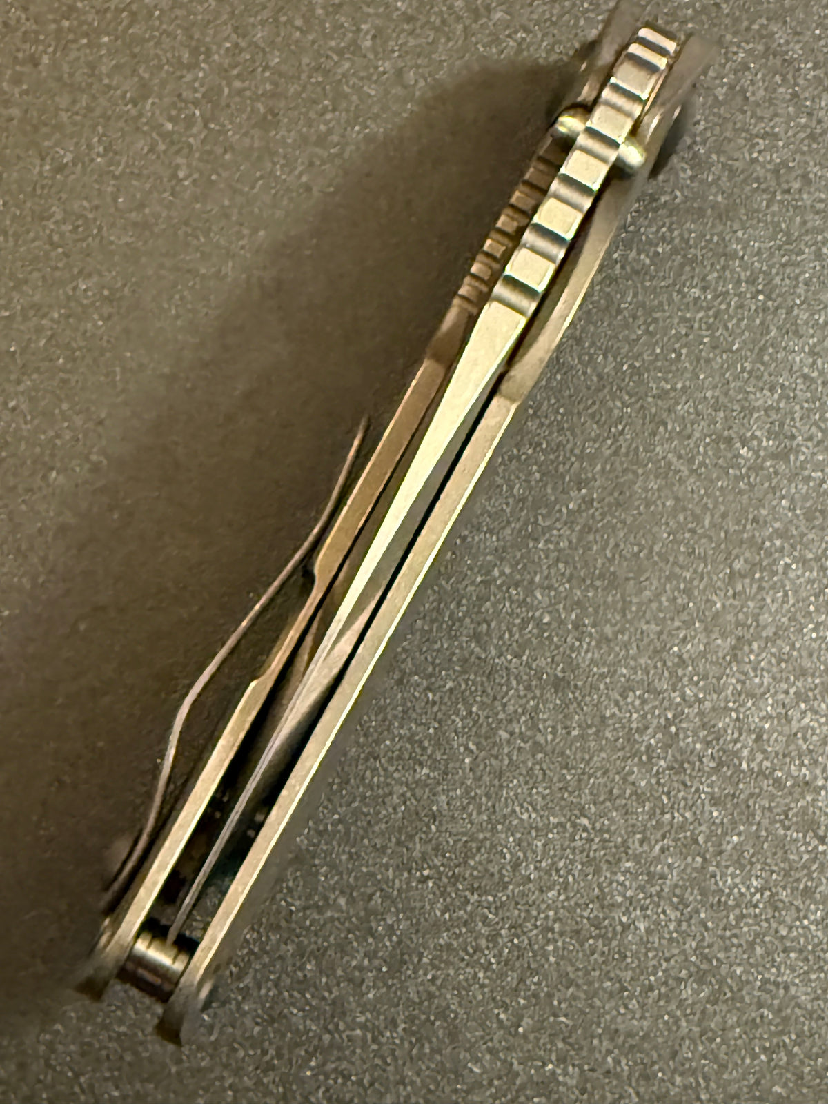 Strider SnG CC full Acid Bronze titanium folding knife showing handle spine, pocket clip, standoffs, and jimping.