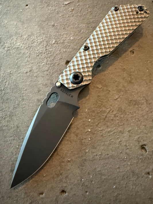 Strider SnG DGG full titanium folding knife with Double Gunner Grip textured handle, black PD1 spear point blade and black titanium hardware.